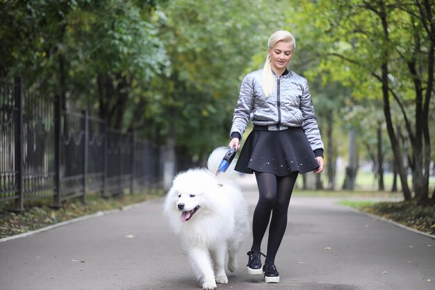 Śliczna dziewczyna na spacerze z pięknym puszystym psem SamoyedxA