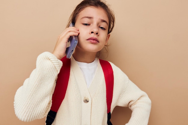 Śliczna dziewczyna rozmawia przez telefon z niezmienionym plecakiem z dzieciństwa