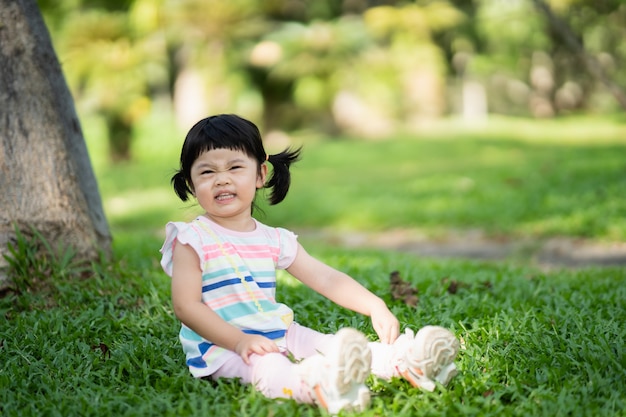 Śliczna dziewczyna siedzi na trawniku w ogrodzie