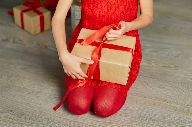 Śliczna dziewczyna trzyma prezenty pudełko w pobliżu choinki rano w domu