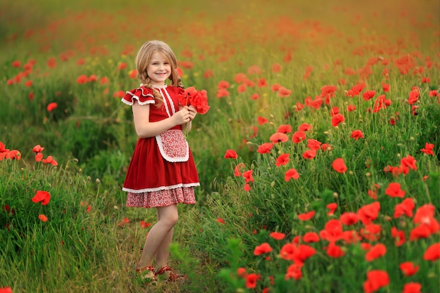 Śliczna dziewczyna w czerwonej sukni na makowym polu