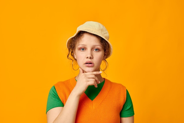 Śliczna dziewczyna w kapeluszu pozowanie pomarańczowy sweter na białym tle