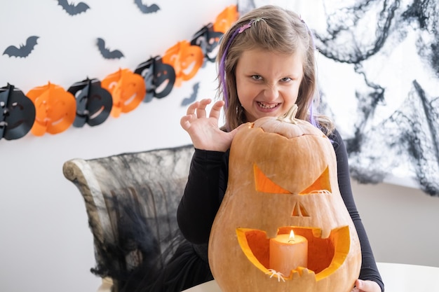 Śliczna Dziewczyna W Stroju Wiedźmy Z Dynią W Domu, Bawiąca Się, świętująca Halloween