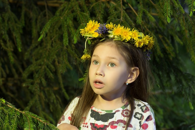 Śliczna dziewczyna w wieniec kwiatów patrzy z jodły w lesie. Młoda wiedźma.