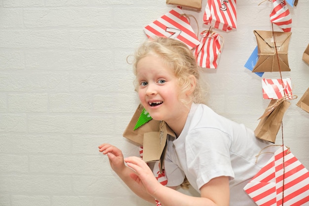 Śliczna dziewczyna z utraconymi zębami dziecka bawi się kalendarzem anwentowym wiszącym na ścianie