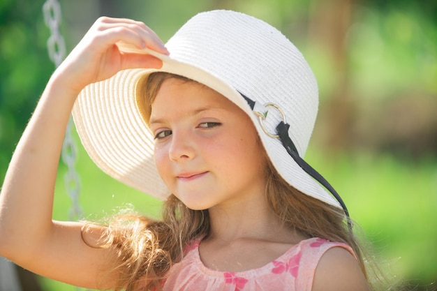 Śliczna dziewczynka kaukaski nosi słomkowy kapelusz stojący na zewnątrz w parku Śmieszne dzieci twarz zbliżenie Portret cute little teen dziewczyna w lecie
