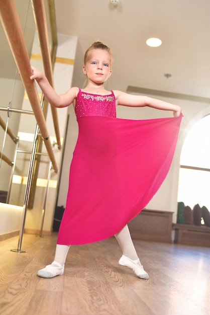 Śliczna dziewczynka marzy o zostaniu baletnicą Dziewczynka w różowej spódniczce tutu tańczy trzymając się baru Dziewczynka uczy się baletu