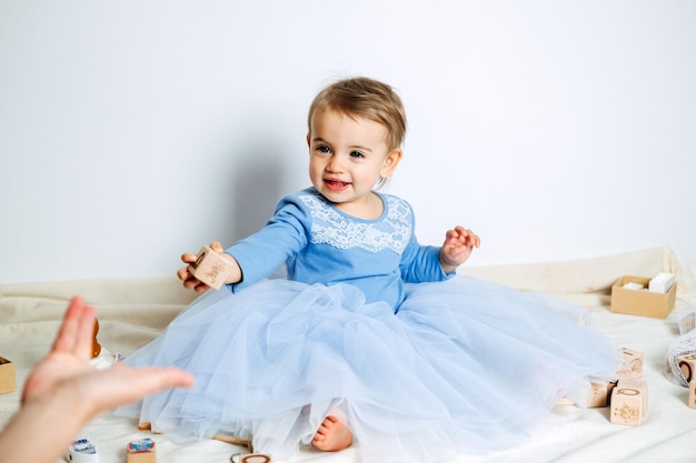 Śliczna dziewczynka w niebieskiej sukience księżniczki bawi się zabawkami z mamą w domu sukienki dla dzieci na urodziny