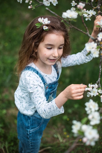 Śliczna dziewczynka w wieku 5 lat w kwitnącym sadzie z białymi jabłkami na wiosnę Wiosenny sad kwitnienie alergia wiosenny zapach czułość troska o przyrodę Portret