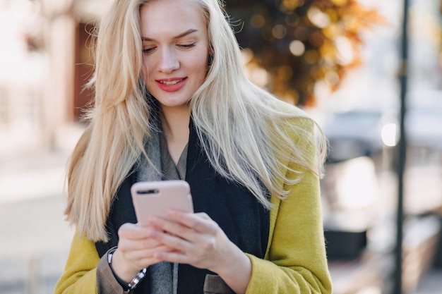 Zdjęcie Śliczna emocjonalna atrakcyjna blondynki kobieta w żakiecie z smartphone chodzi miasto ulicę. komunikacja podczas spaceru, stylu życia, ulicy.