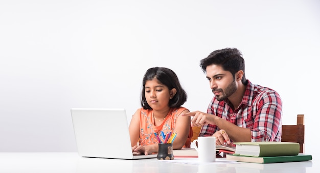 Śliczna Indyjska Dziewczyna Z Ojcem Studiuje Lub Odrabia Pracę Domową W Domu Za Pomocą Laptopa I Książek - Koncepcja Edukacji Online