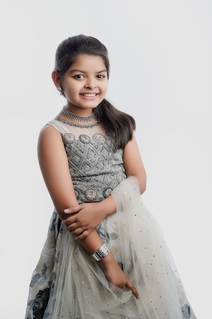 Śliczna indyjska dziewczynka w etnicznym stroju i pokazująca ekspresję na białym tle