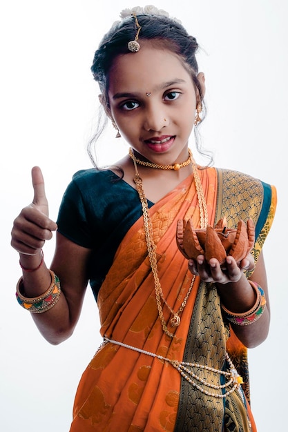 Śliczna indyjska maharasztriańska dziewczynka trzyma lampę w ręku i świętuje tradycyjny festiwal Raksha Bandhan lub Diwali