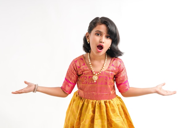 Śliczna indyjska mała dziewczynka daje wyrazowi na białym tle