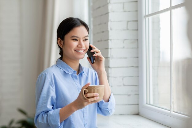 Śliczna japońska dama pije kawę i rozmawia przez telefon