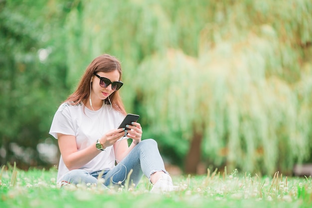 Śliczna kobieta czyta wiadomość tekstową na telefonie komórkowym podczas gdy siedzący w parku.