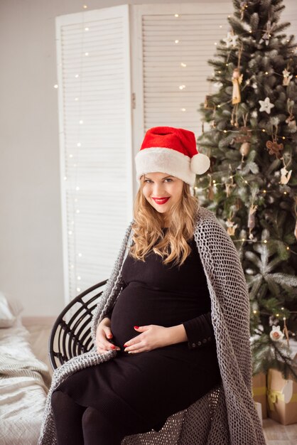 Śliczna kobieta w ciąży w kapeluszu Santa