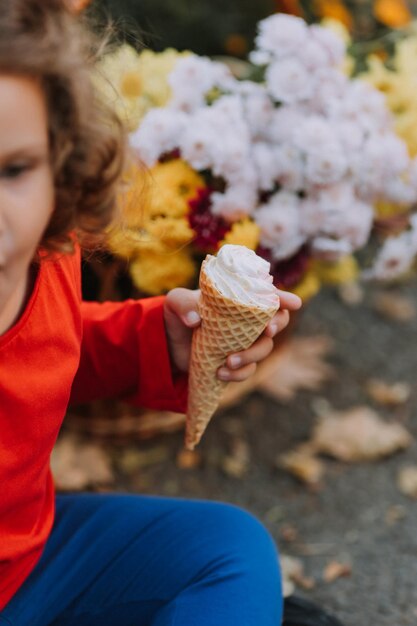 śliczna kręcona mała dziewczynka je lody w parku jesień jesień karta kwiaty sztandar