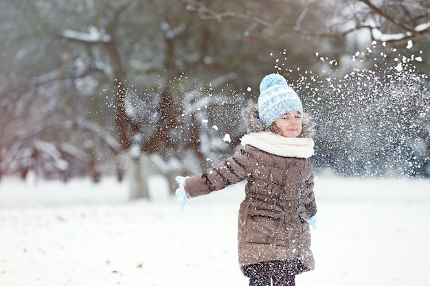 Śliczna mała dziewczynka bawi się śniegiem w winter park