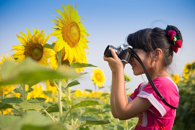 Śliczna mała dziewczynka bierze obrazek z rocznik kamerą w słonecznika polu.