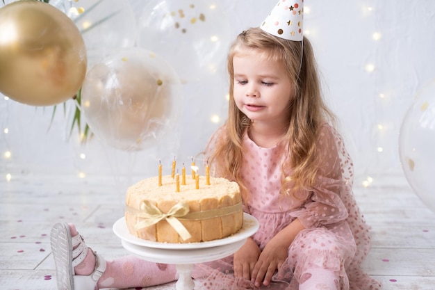 Śliczna mała dziewczynka dmuchająca świeczki na tort urodzinowy i świętująca urodziny
