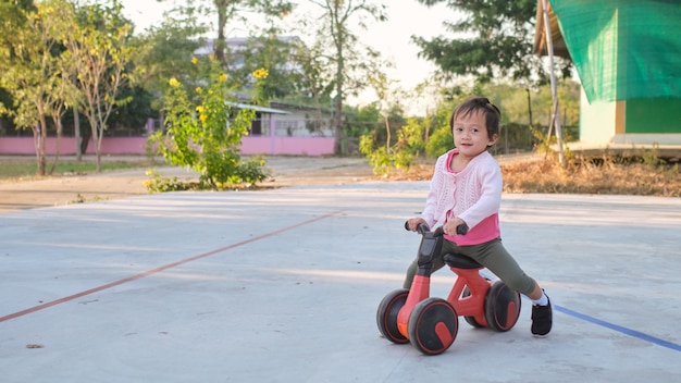 Śliczna mała dziewczynka dziecko uczy się jeździć na pierwszym rowerze równowagi dzieci na rowerze w parku