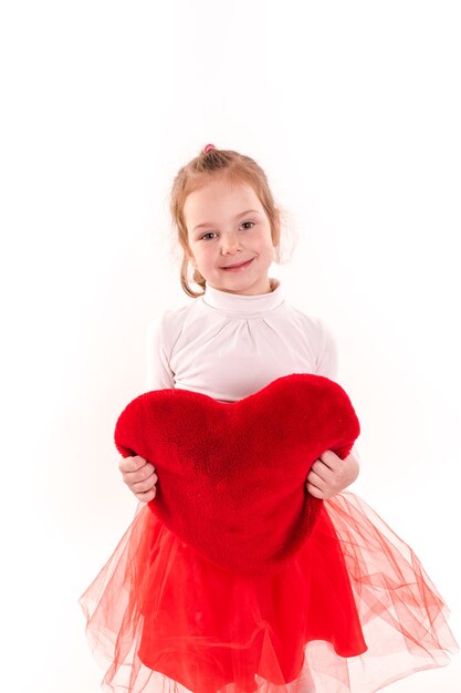 Śliczna mała dziewczynka gospodarstwa czerwone serce na białym tle. Koncepcja Świętego Walentego, miłości i szczęścia.