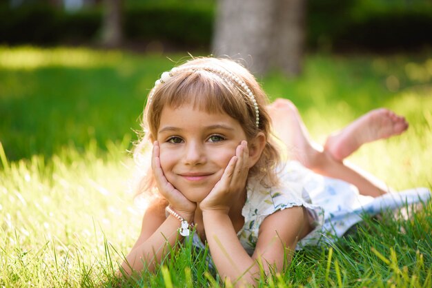 Śliczna mała dziewczynka kłama na trawie w lato parku