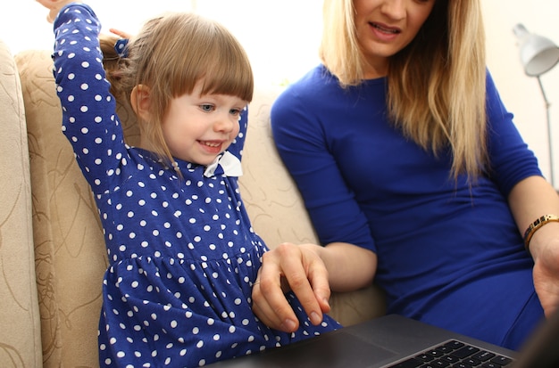 Śliczna mała dziewczynka na kanapie z mamą za pomocą laptopa