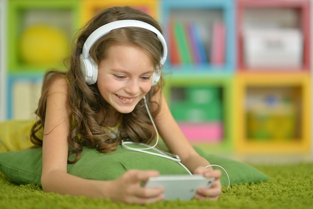 Śliczna mała dziewczynka słucha muzykę ze smartfonem i słuchawkami