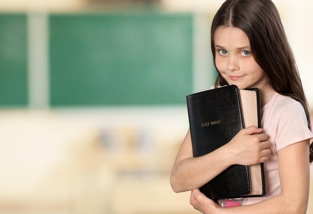 Śliczna mała dziewczynka trzyma Biblię na tle