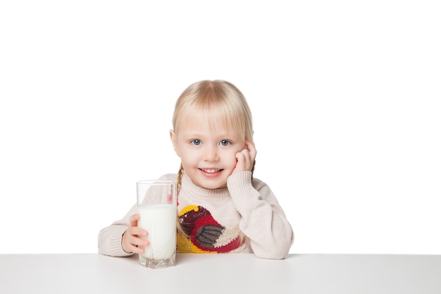 Śliczna mała dziewczynka trzyma kubek mleka, na białym tle