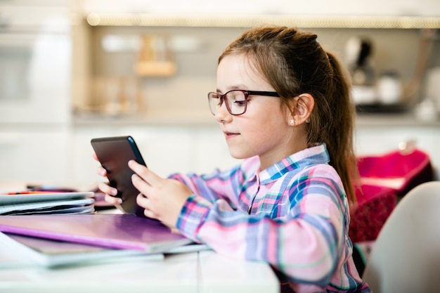 Śliczna Mała Dziewczynka Trzyma Tablet Podczas Odrabiania Lekcji