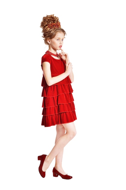Śliczna mała dziewczynka w czerwonej aksamitnej sukience z retro fryzurą na białym tle
