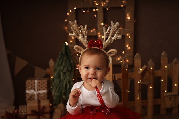 śliczna mała dziewczynka w stroju noworocznym podgryza noworocznego lizaka
