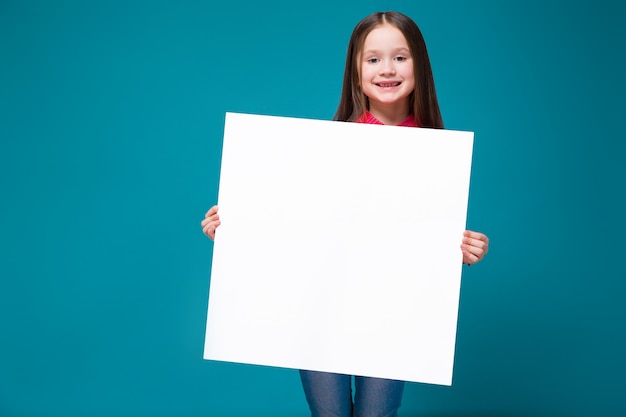 Śliczna mała dziewczynka w w kratkę koszula z brunet włosy trzyma jasnego papier