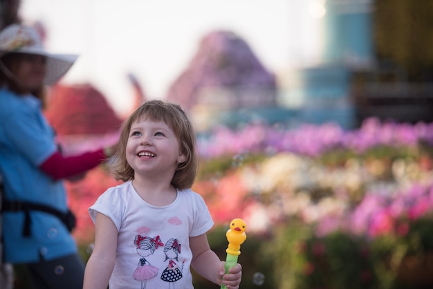 śliczna mała dziewczynka z lalką w dłoniach w pięknym ogrodzie kwiatowym