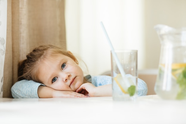 Zdjęcie Śliczna mała dziewczynka z szkłem woda w kuchni