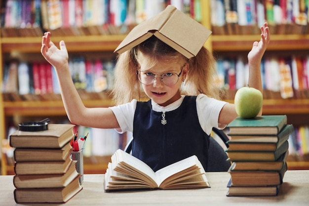 Śliczna mała dziewczynka z warkoczykami jest w bibliotece