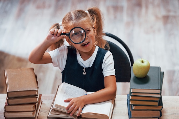 Śliczna mała dziewczynka z warkoczykami jest w bibliotece