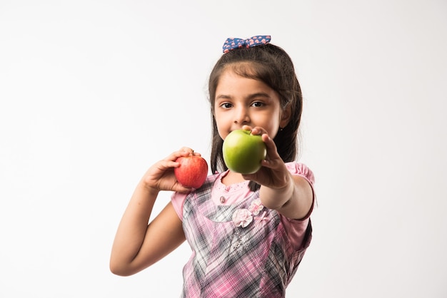 Śliczna mała indyjska lub azjatycka dziewczyna trzyma owoce zielone i czerwone jabłko - koncepcja zdrowego odżywiania