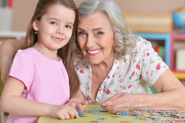 Śliczna mała wnuczka i babcia zbiera puzzle