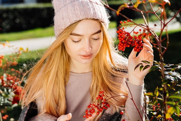 Śliczna młoda blond dziewczyna w kapeluszu spacerująca po ogrodzie, ciesząca się przyrodą i słońcem, wiosna
