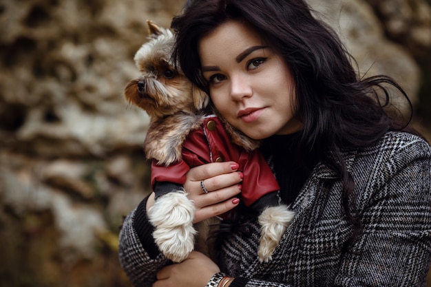 Śliczna młoda dziewczyna z psem yorkshire terrier w parku jesienią. koncepcja opieki i przyjaźni