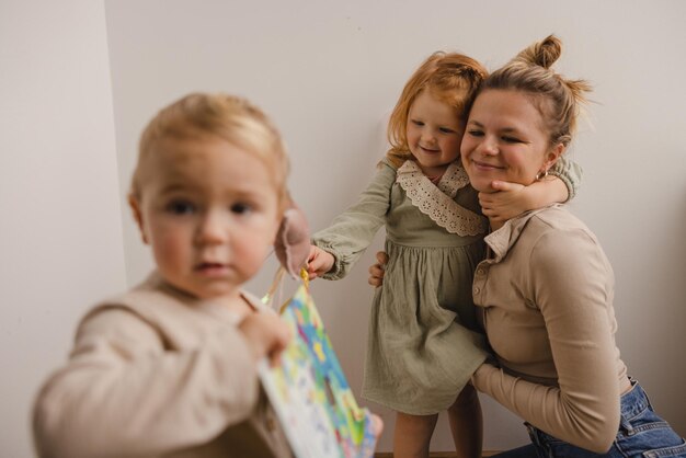 Śliczna młoda kaukaska matka przytulająca swoją małą rudowłosą córkę bawiącą się z dziećmi w domu w weekendy Koncepcja rodziny