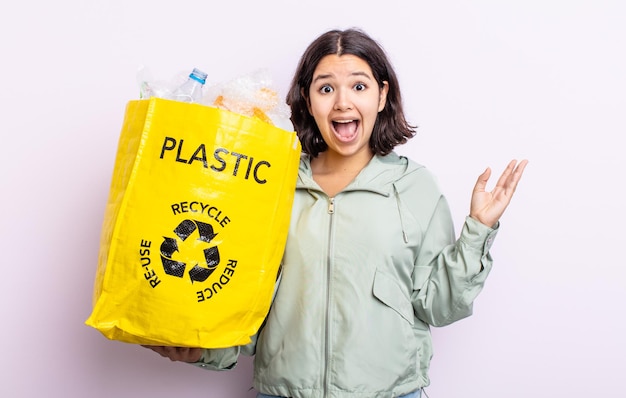 Śliczna młoda kobieta czuje się szczęśliwa i zdumiona czymś niewiarygodnym. koncepcja recyklingu tworzyw sztucznych