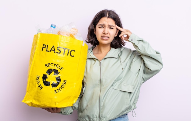 Śliczna młoda kobieta czuje się zdezorientowana i zdezorientowana, pokazując, że jesteś szalony. koncepcja recyklingu tworzyw sztucznych