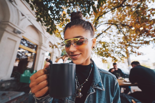 Zdjęcie Śliczna młoda kobieta podczas picia herbaty w nowoczesnej ulicznej kawiarni