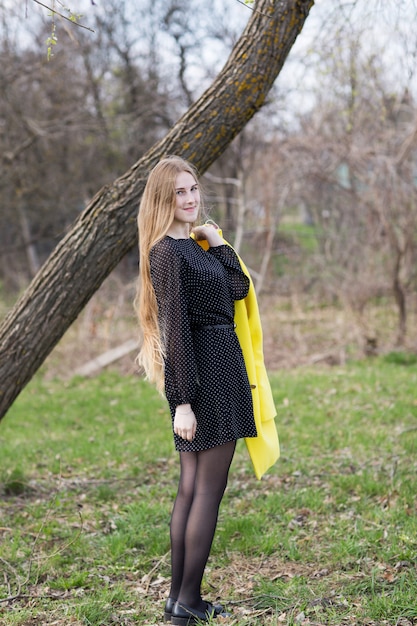 Śliczna młoda kobieta z długimi włosami w żółtym płaszczu