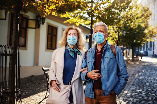 Śliczna Para Seniorów W Maskach Ochronnych Na Wspólnym Spacerze W Starej Części Miasta.